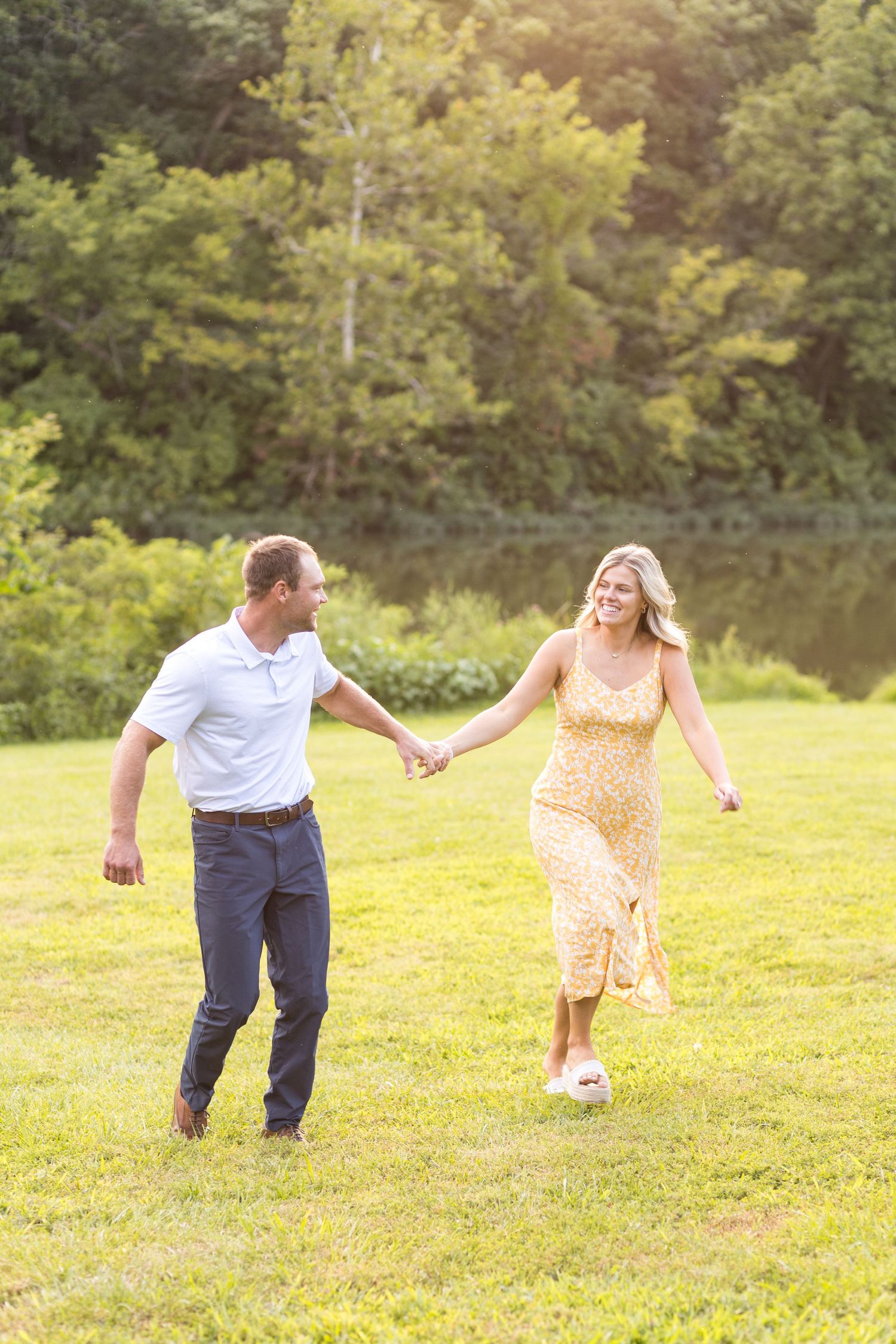 Engaged couple holding hands and running in a field
