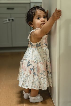 Small toddler holding onto a kitchen island to stand and take a step.