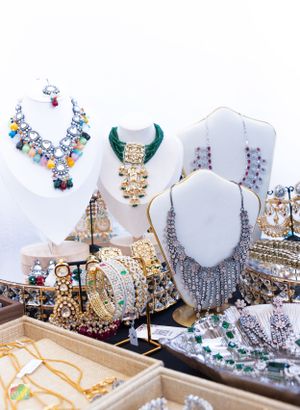 Display of ornate statement necklaces and jewelry on white mannequin busts in a retail setting.