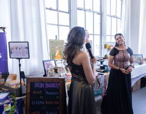Vendor booth setup at an indoor market with signage and displays near large windows.