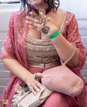 Detailed view of ornate Indian jewelry and beaded clutch with pink embellished clothing.