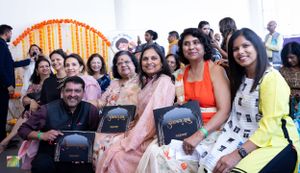 Festival audience members seated and smiling during cultural event with orange decor.