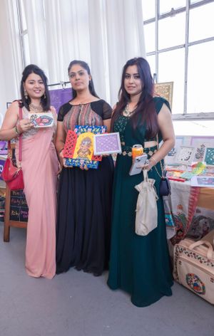 Three vendors showcase colorful books and merchandise at festival booth.