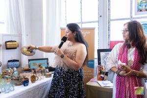 Presenters showcase products at a vendor table during an indoor event.