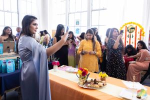 A presenter addresses an audience at an indoor event with food displays and decorations.