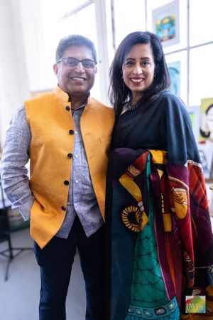 Two individuals in formal attire at an event, one wearing a yellow nehru jacket and one in a black outfit with colorful details.