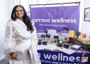 A wellness vendor booth display with purple banner and natural products showcased on table.