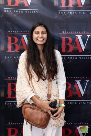 A person in white ethnic wear posing against BAV media backdrop.