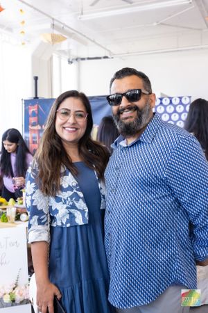 Two people in casual attire smiling at outdoor vendor market event.