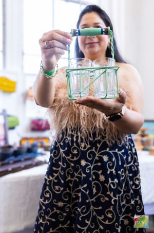 Person holding decorative glass lantern with intricate green details.