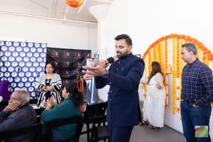 People gathered at decorated event space with orange and white floral arrangements.