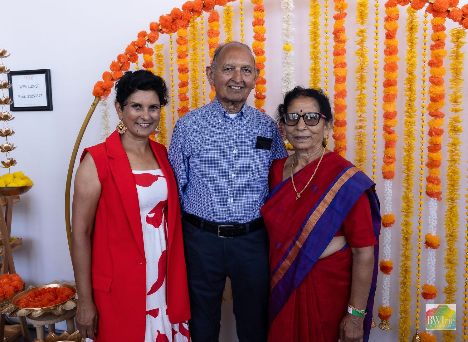 Group photo against orange and yellow flower backdrop at cultural celebration.