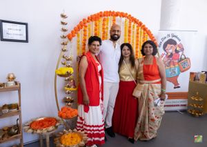 Group gathering in traditional Indian attire against floral decorated backdrop.