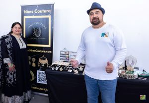 Jewelry vendor displaying handcrafted pieces at craft market booth.