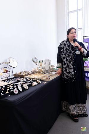 Jewelry vendor displays elegant collection on black-draped table at artisan market event.