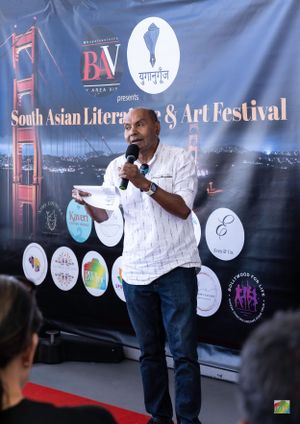 Speaker presenting at South Asian Literature & Art Festival with Golden Gate Bridge backdrop.