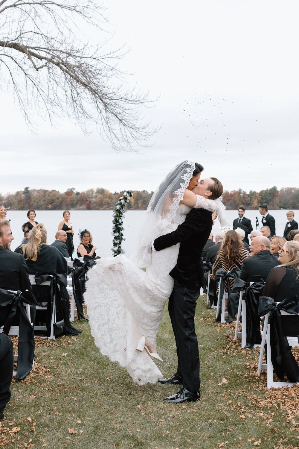 A romantic wedding ceremony dip pose with guests watching in an autumn outdoor setting.