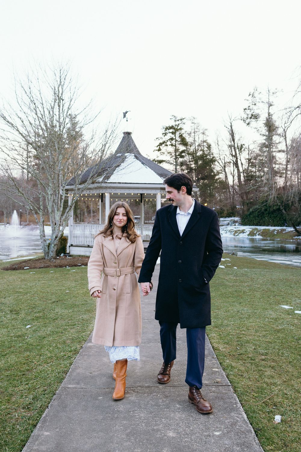 A couple strolls together on a concrete path through a winter landscape. Château des  Fleures Wedding Photographer