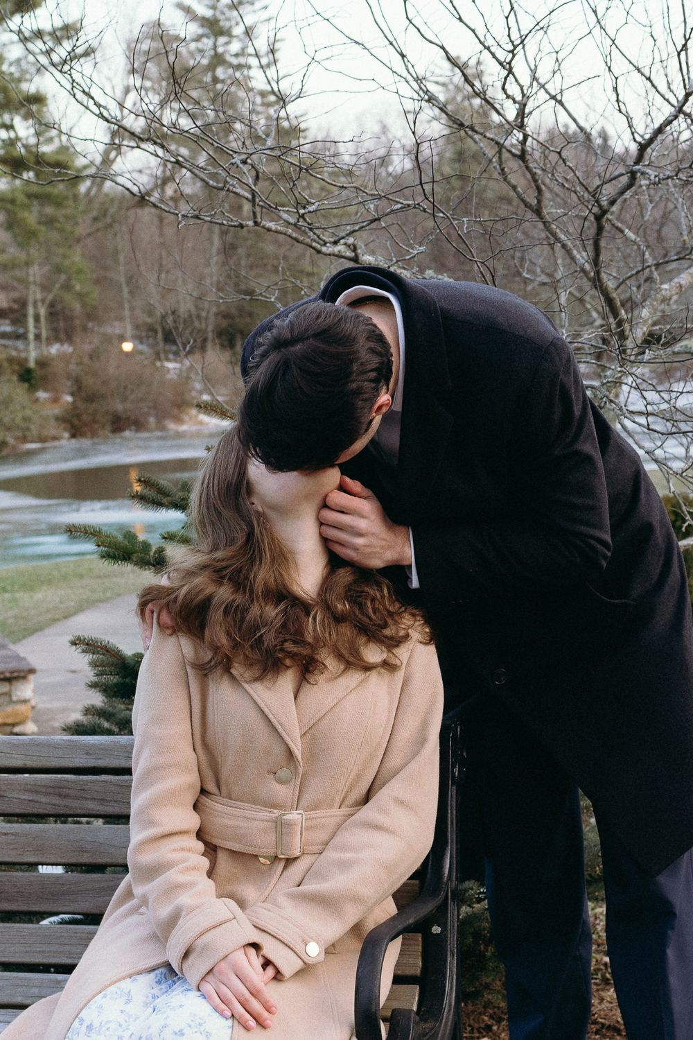 A couple shares a tender moment while sitting on a park bench in winter. Castle  Ladyhawke Wedding Photographer