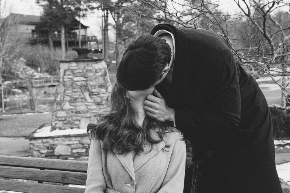 A couple shares an intimate moment on a wooden park bench surrounded by winter trees. Castle  Ladyhawke Wedding Photographer