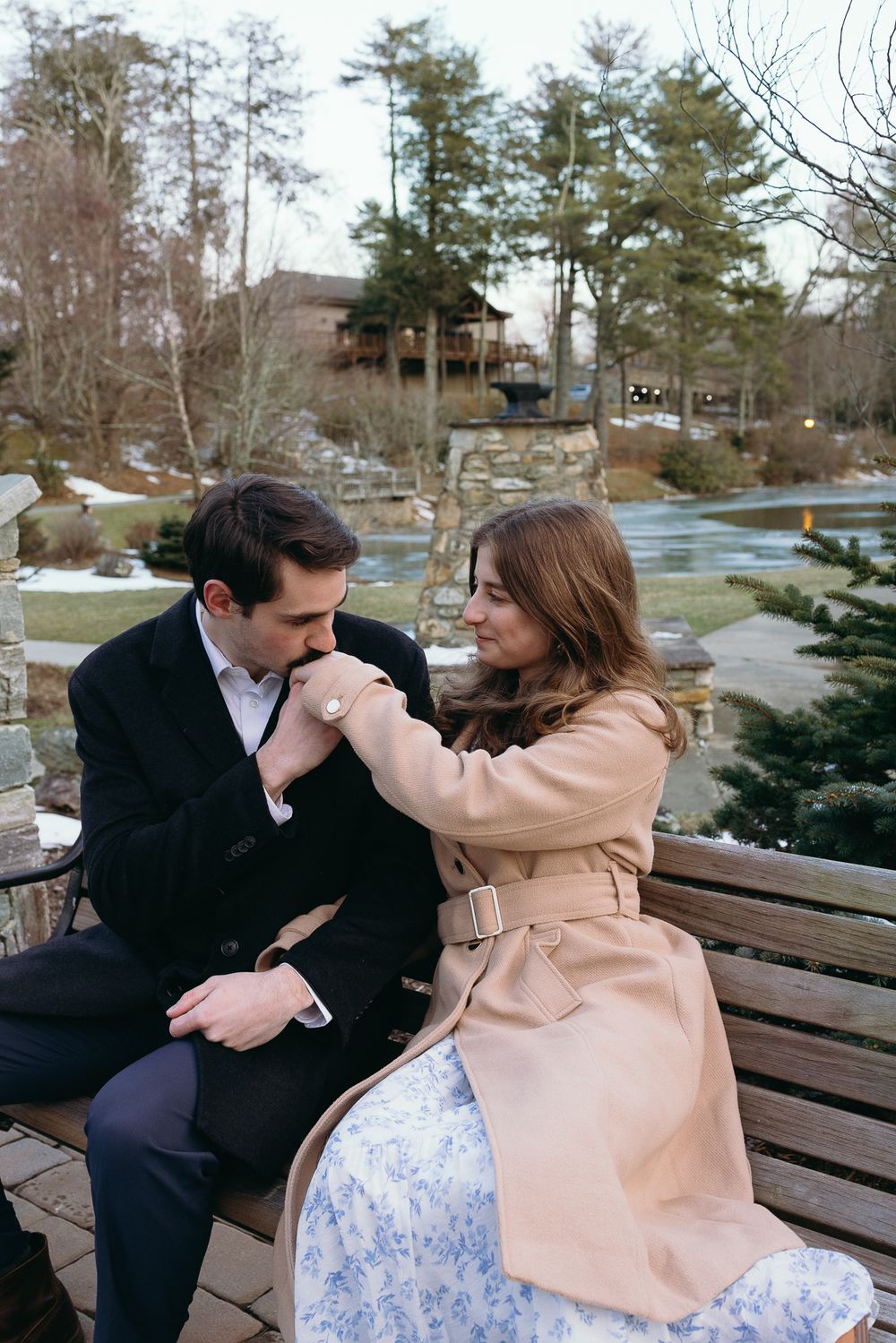 A couple in winter attire shares affectionate moments on a park bench surrounded by evergreen trees. Castle  Ladyhawke Wedding Photographer