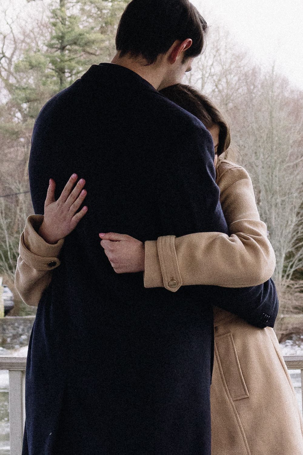 A couple shares an intimate moment wearing winter coats outdoors. Château des  Fleures Wedding Photographer