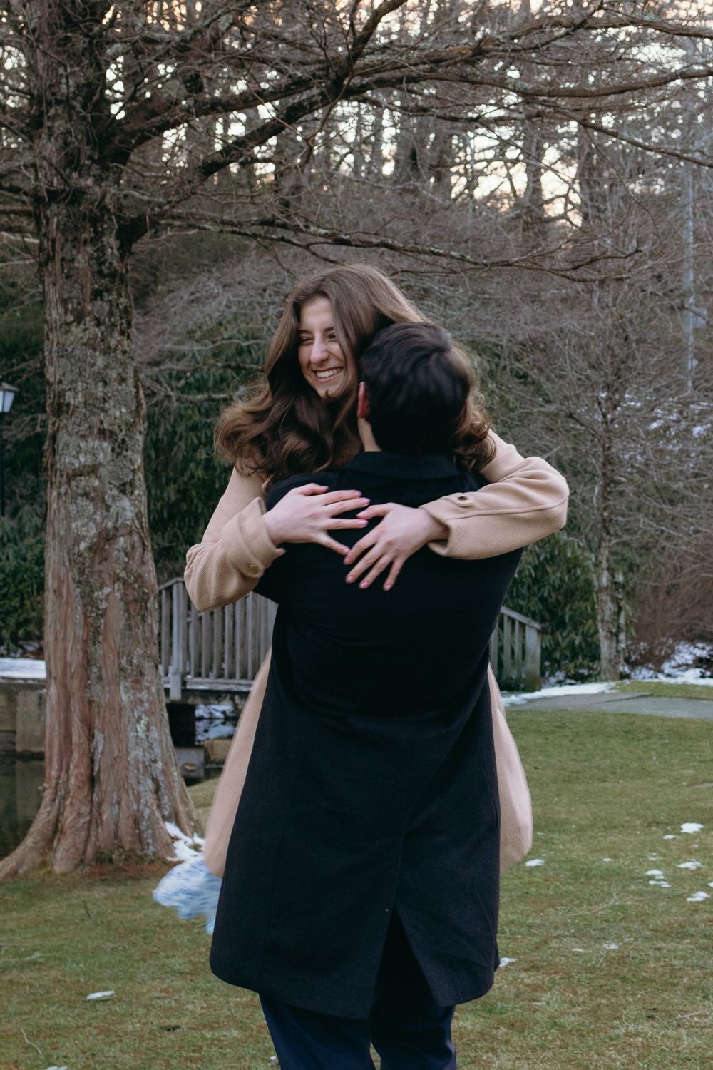 Two people share a warm embrace while standing in a winter park with snow patches visible. Castle  Ladyhawke Wedding Photographer