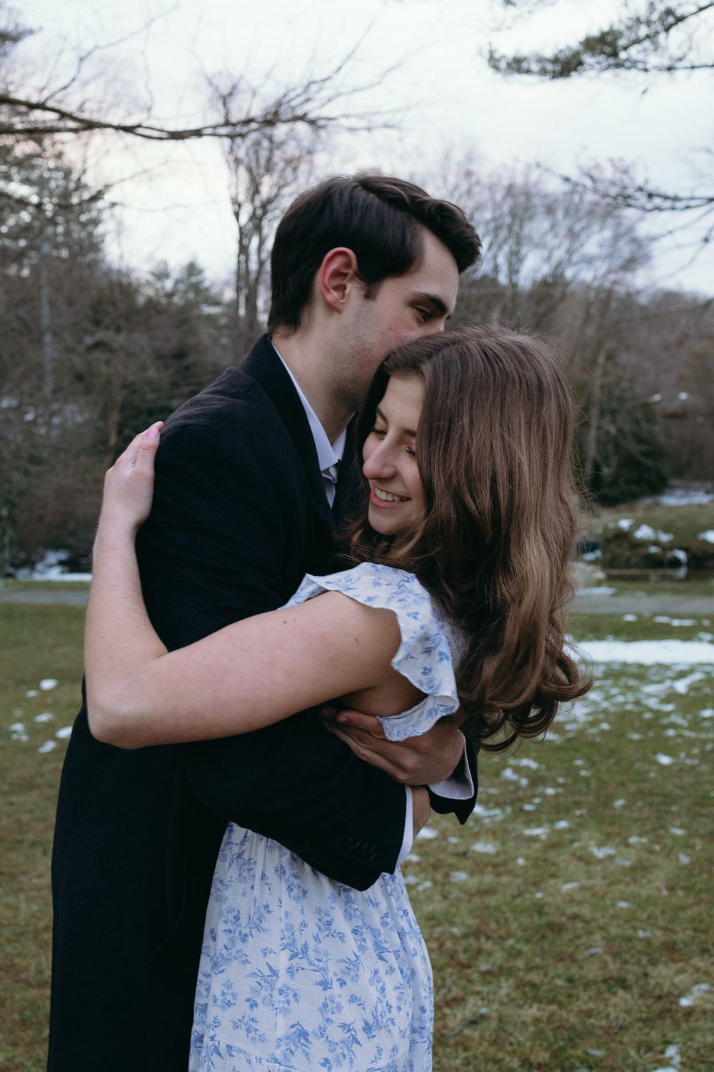 A couple embraces tenderly in a park setting with patches of snow on the ground. Castle  Ladyhawke Wedding Photographer