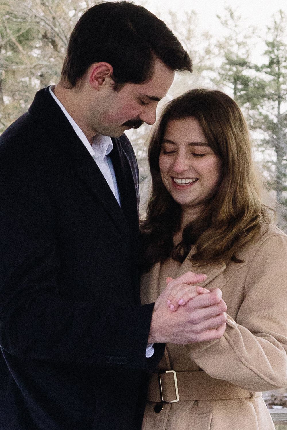 A tender moment between two people in winter coats against a natural backdrop. Château des  Fleures Wedding Photographer