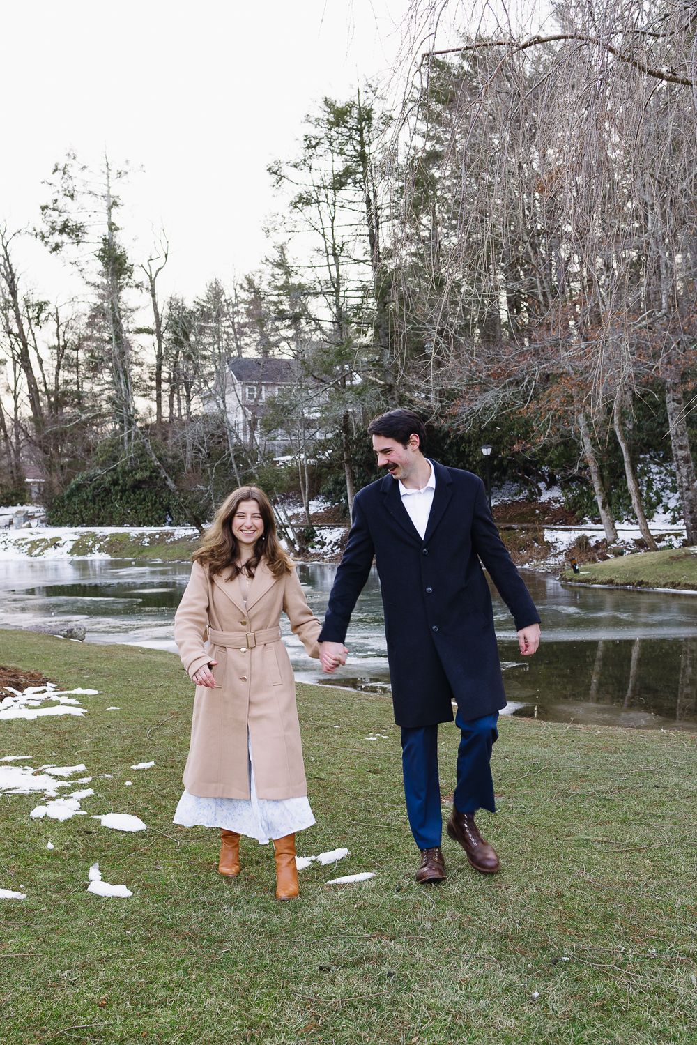 A couple strolls through a winter park with patches of snow and bare trees. Château des  Fleures Wedding Photographer