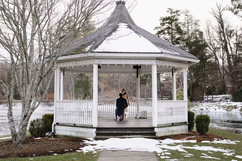 A white gazebo stands in a snowy winter landscape surrounded by bare trees. Château des  Fleures Wedding Photographer