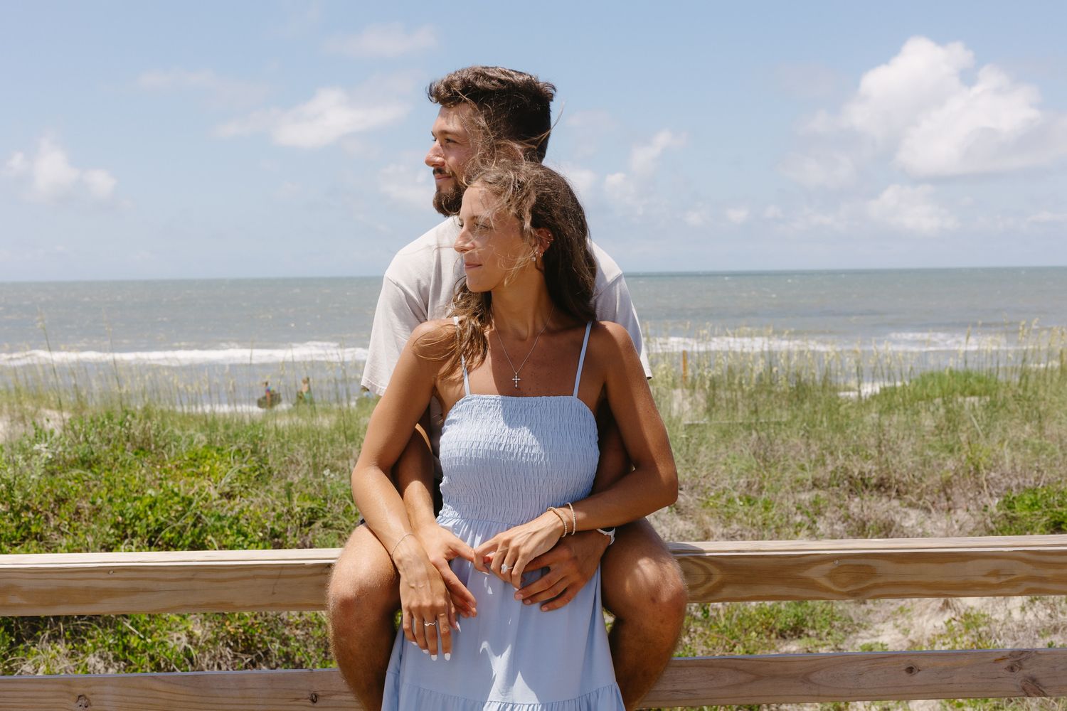 Engaged couple stare off at the beach right after he proposed.