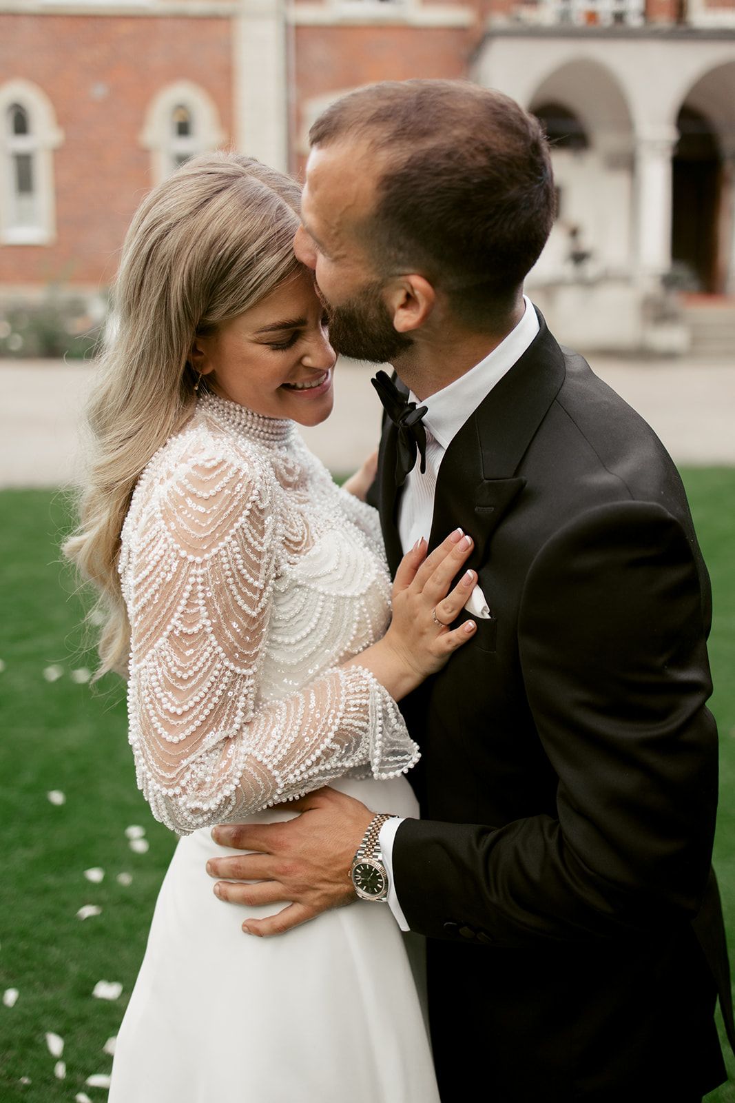 Romantic couple in elegant wedding attire sharing intimate moment on castle grounds.