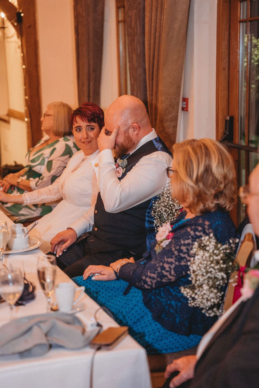 Wedding reception guests seated at decorated tables in an elegant venue with warm lighting.