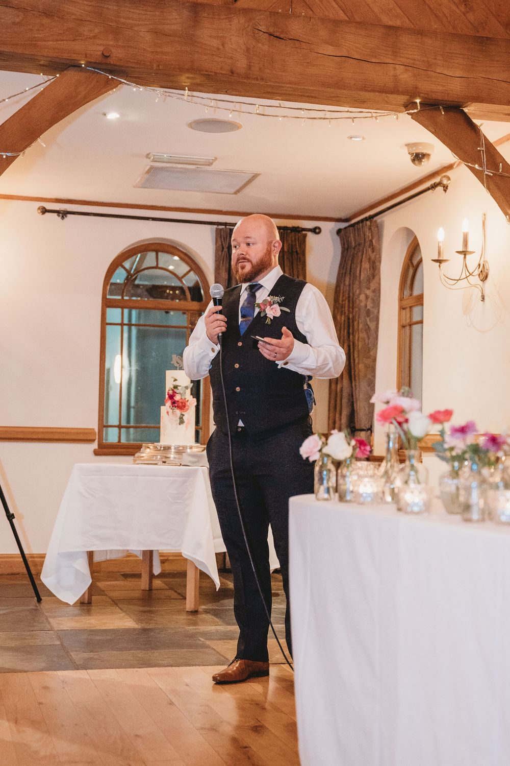 Wedding reception setup in a rustic venue with white tablecloths and floral centerpieces.
