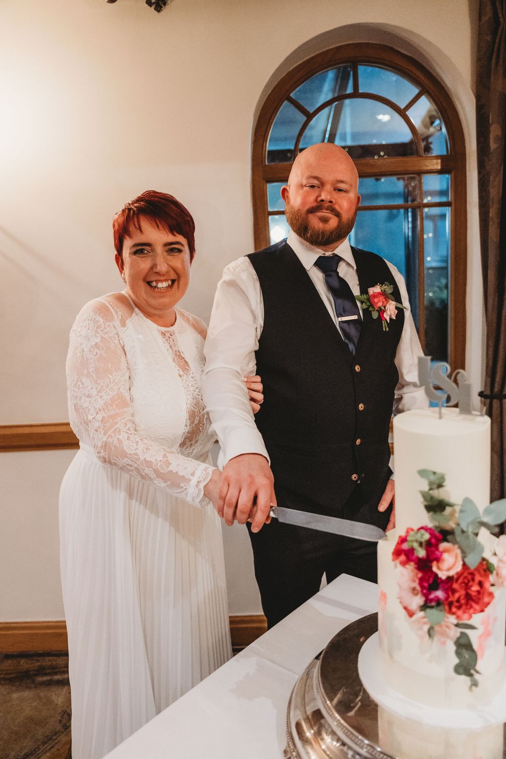 Newlyweds share a moment while cutting their wedding cake at reception.