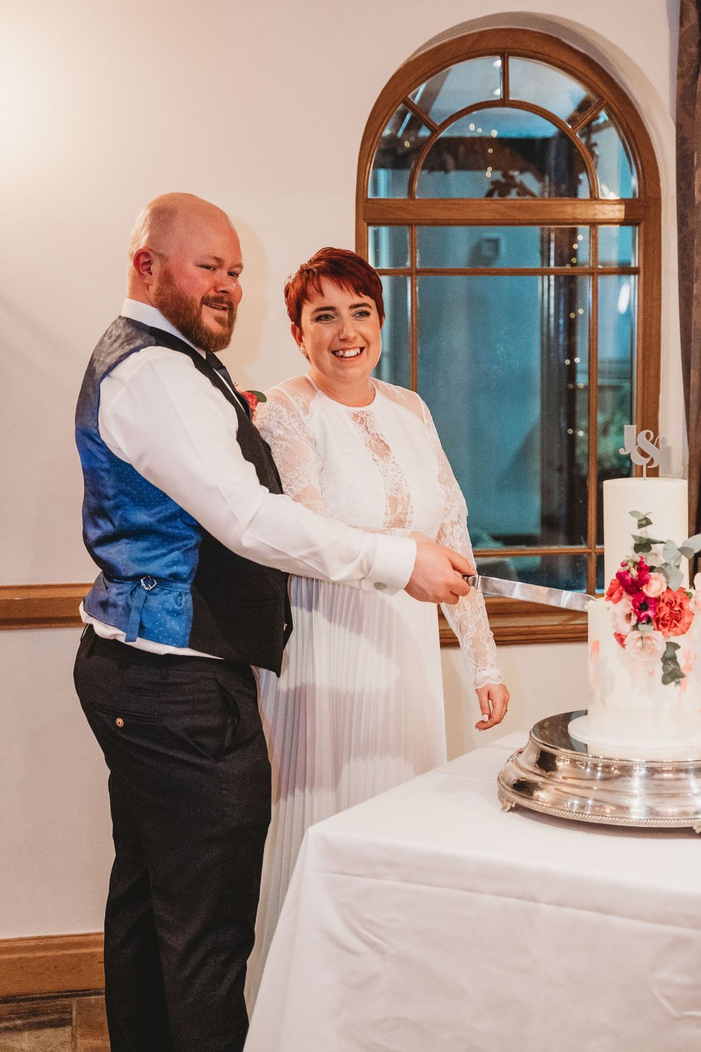 Couple cutting their wedding cake together at elegant reception venue.
