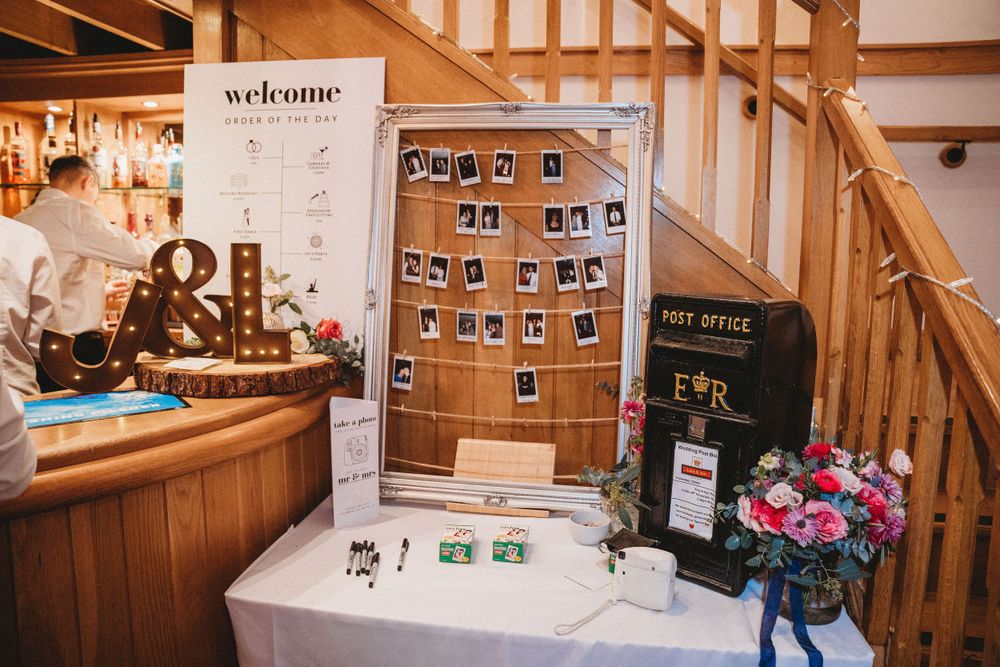 Wedding reception decor featuring photo displays and welcome signs in rustic wooden venue.
