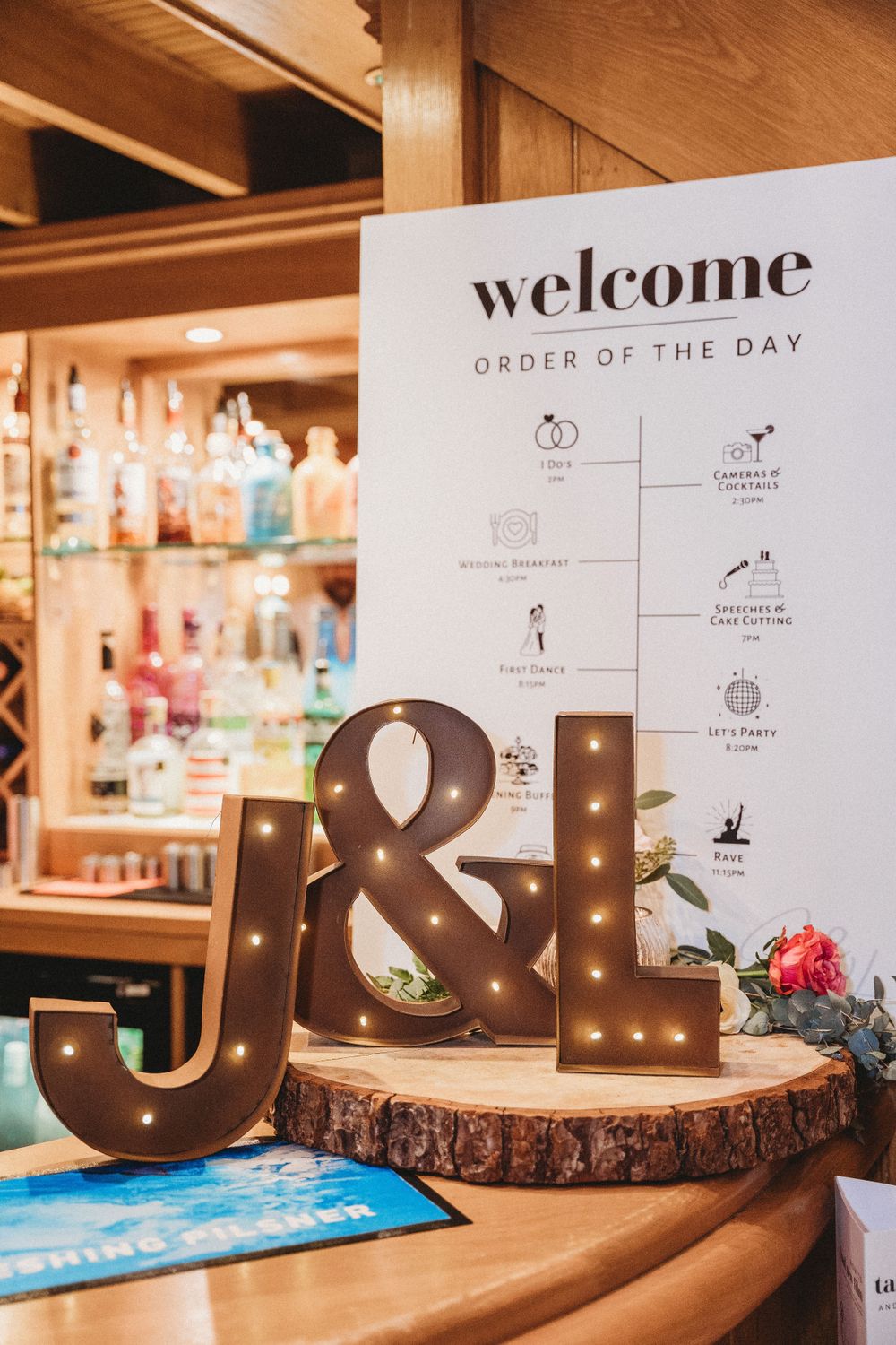 Illuminated wooden letters spell out welcome message at wedding reception with decorative signage.