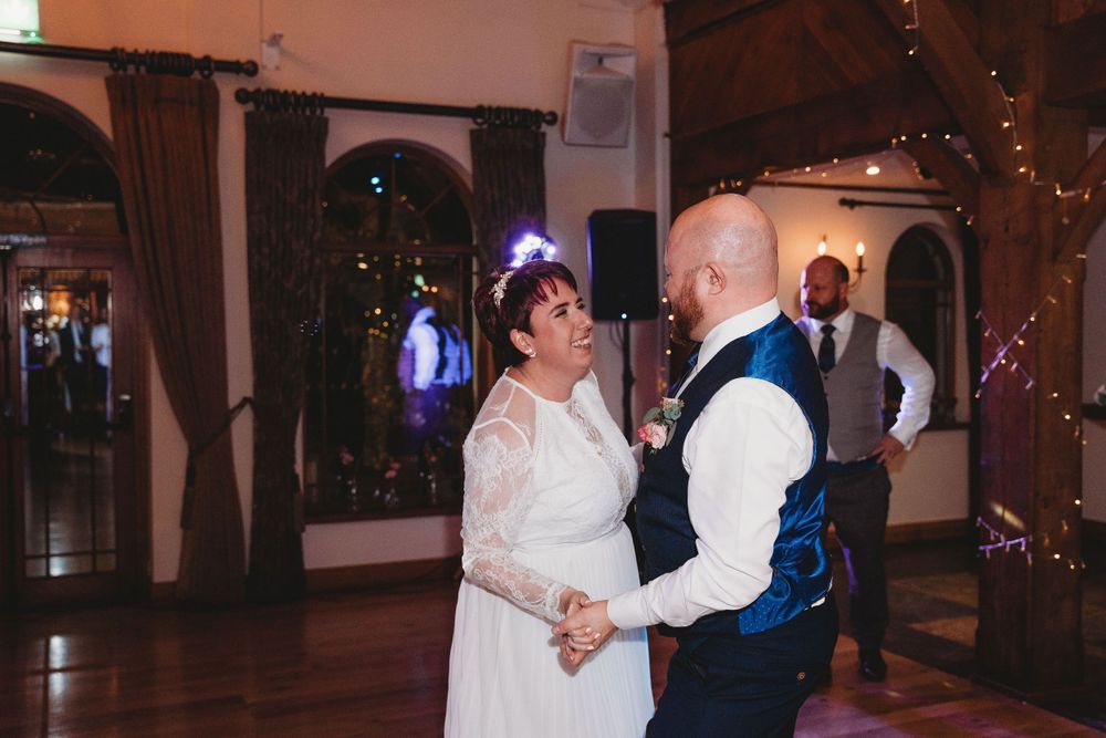 Couples slow dancing on a wooden dance floor at an evening wedding celebration.