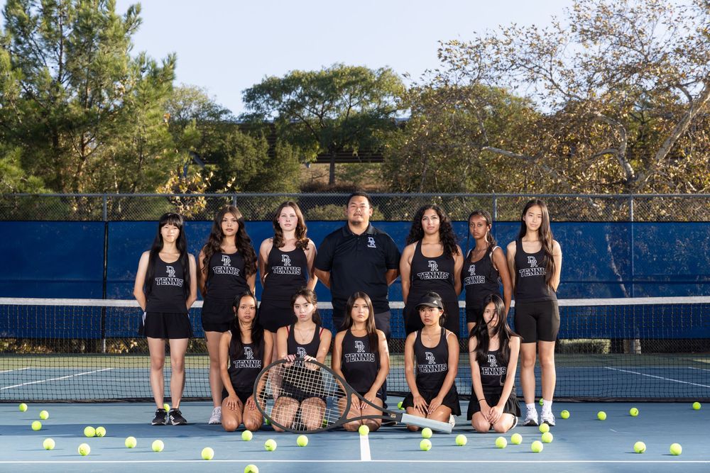 Tennis players line up on outdoor courts for team photos during a sunny afternoon practice session.