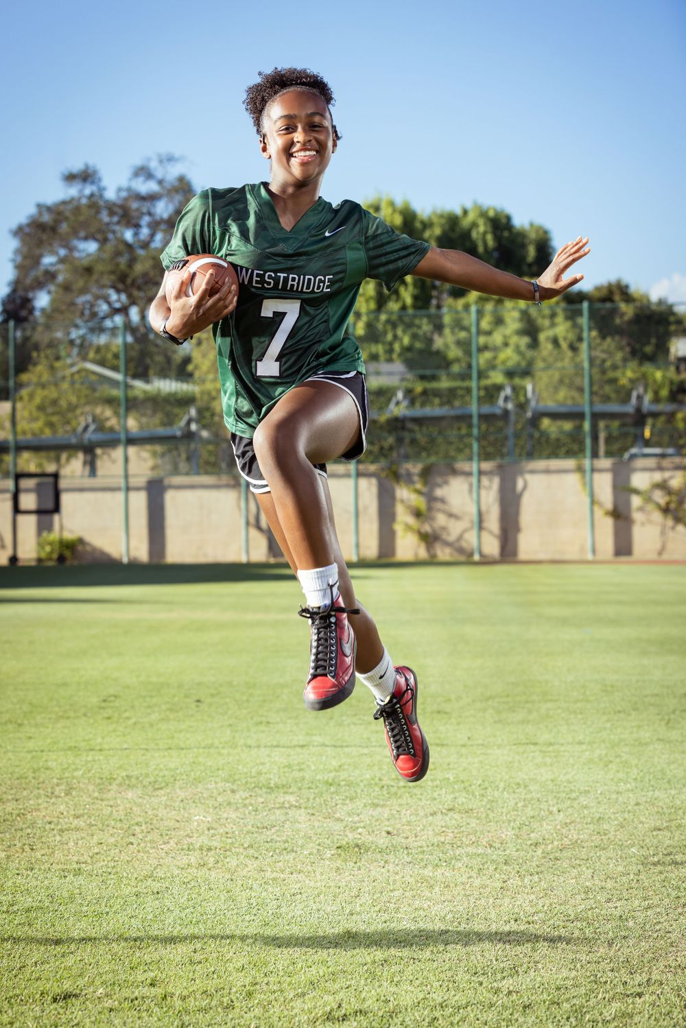 Three action shots of a young athlete in a green jersey jumping and kicking on a sunny sports field.