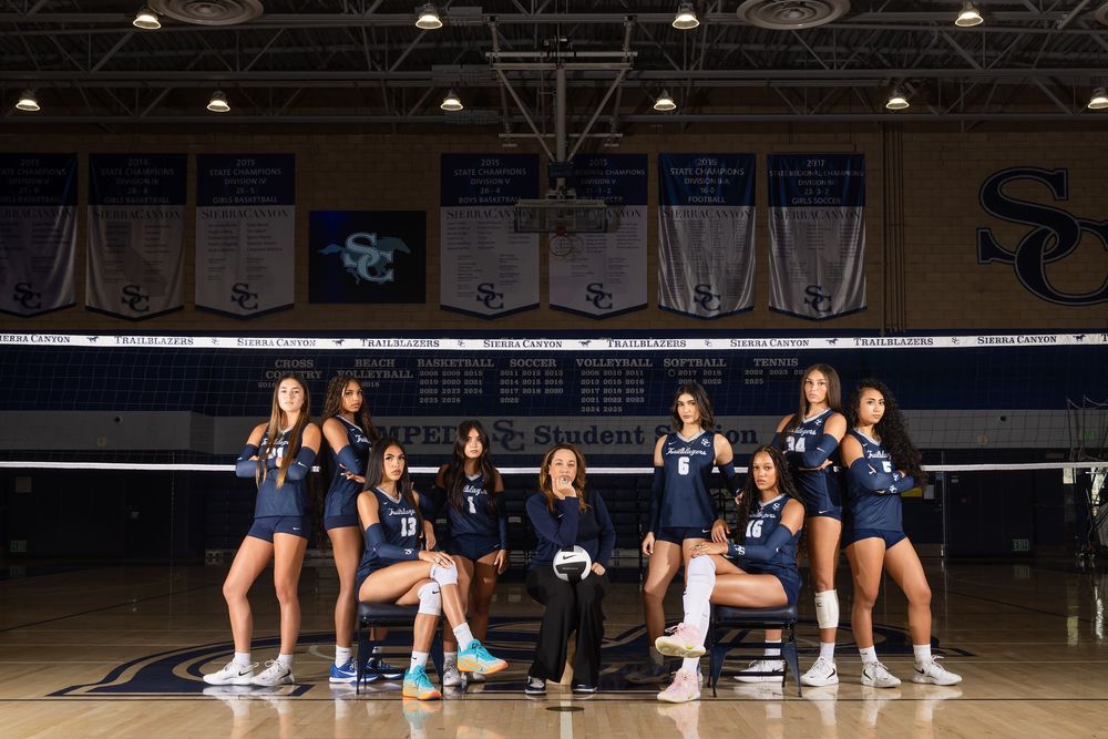 Sierra Canyon high school girls volleyball team poses with coach in gymnasium.