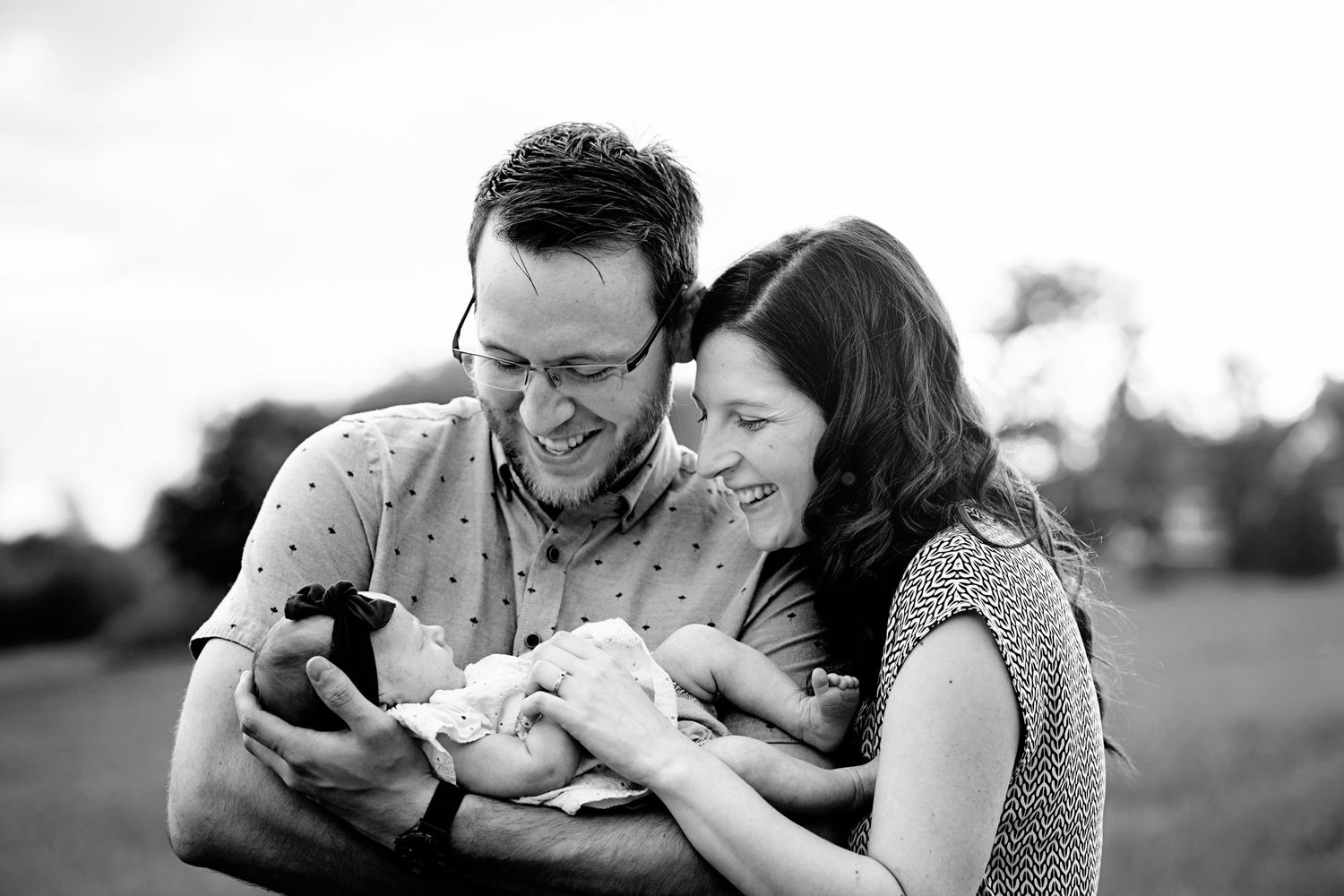 A tender black and white outdoor moment shared with a newborn baby on a summer day.