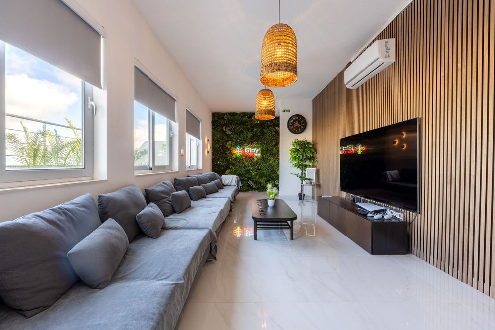 Modern living room with grey sectional sofa, wooden accent wall, and hanging rattan pendant lights.
