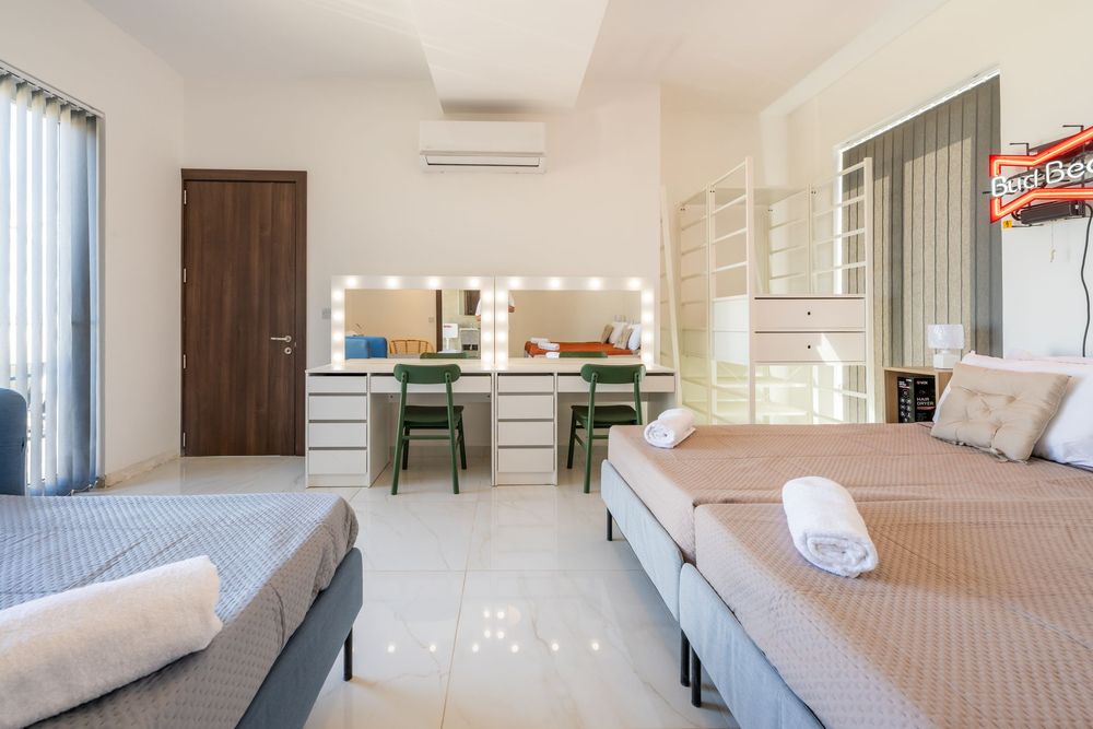Bedroom with twin beds, vanity area, and kitchen visible in open floor plan layout.
