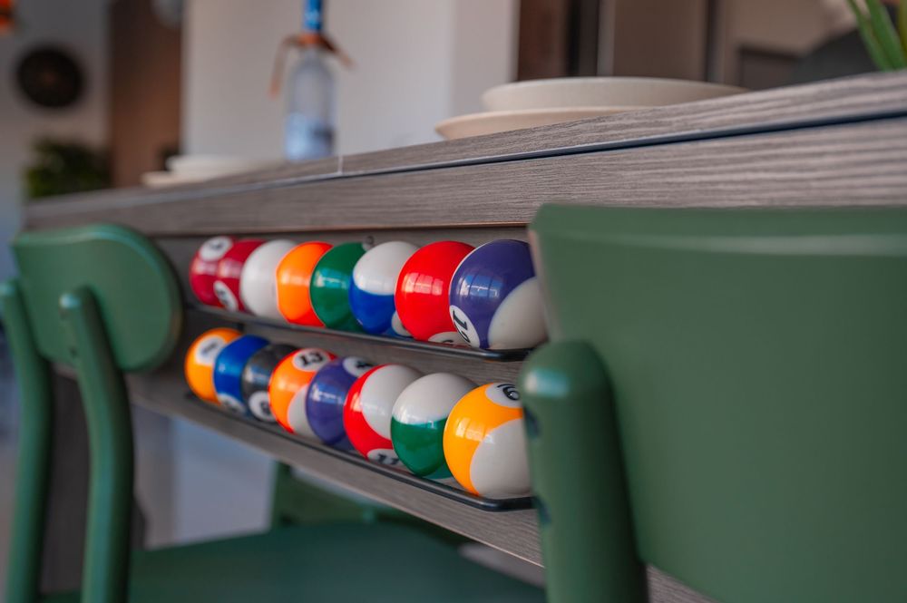 Pool table with colorful billiard balls lined up along the green felt surface.