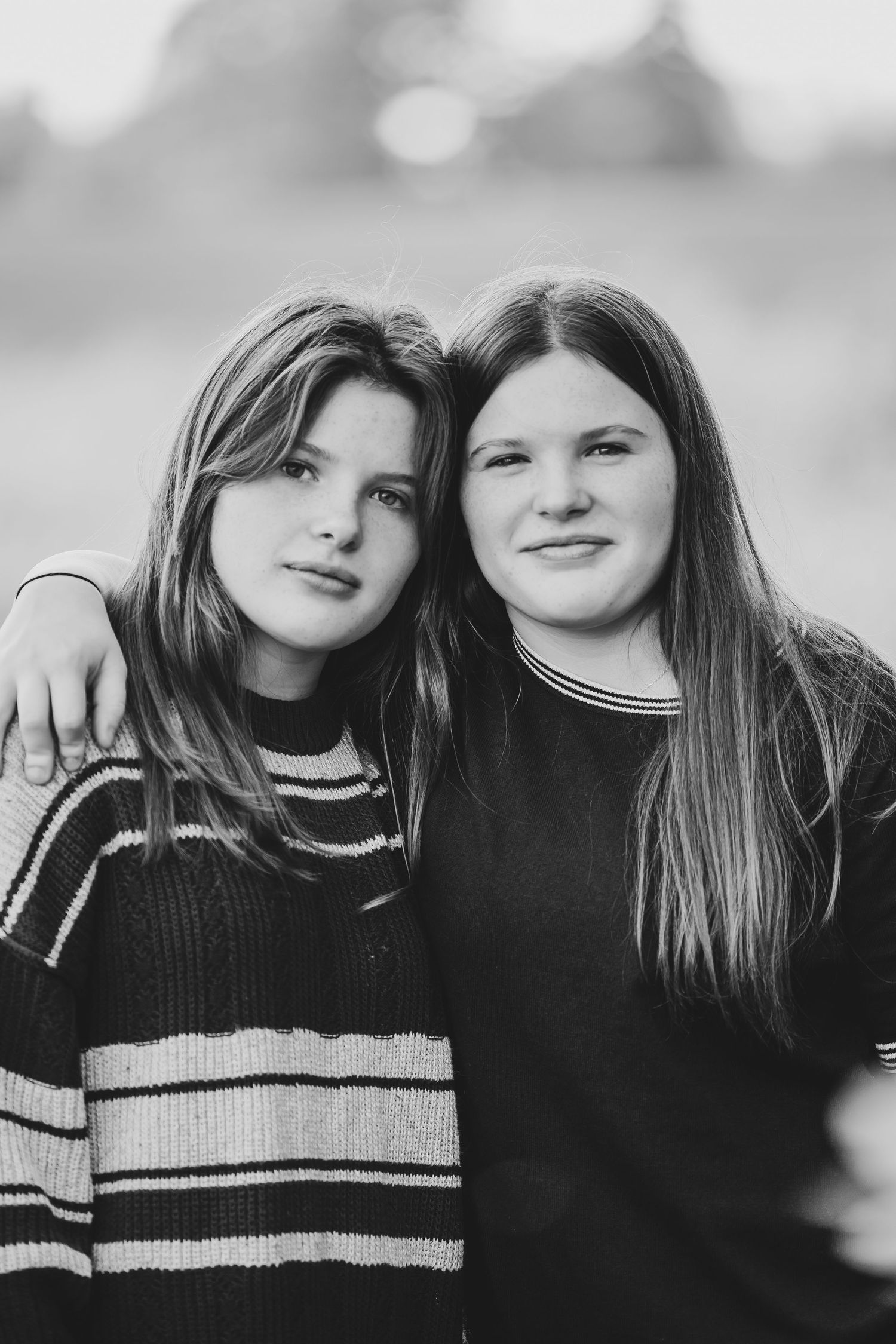Black and white portrait of two friends in striped and solid sweaters.
