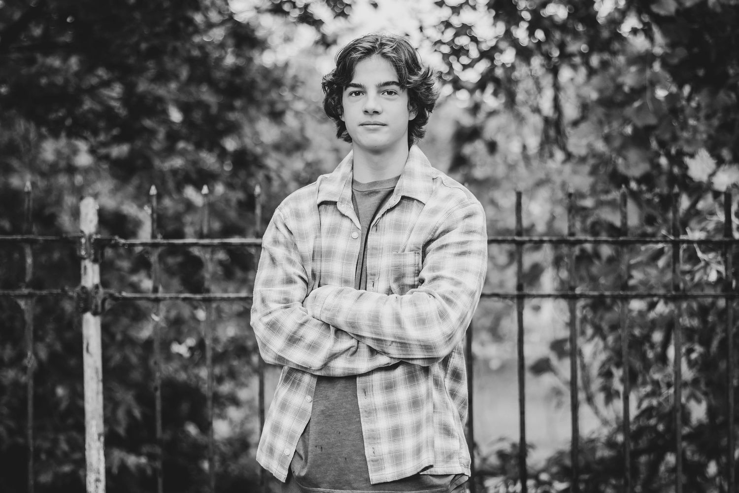 Black and white portrait series showing casual outdoor poses against a natural background.