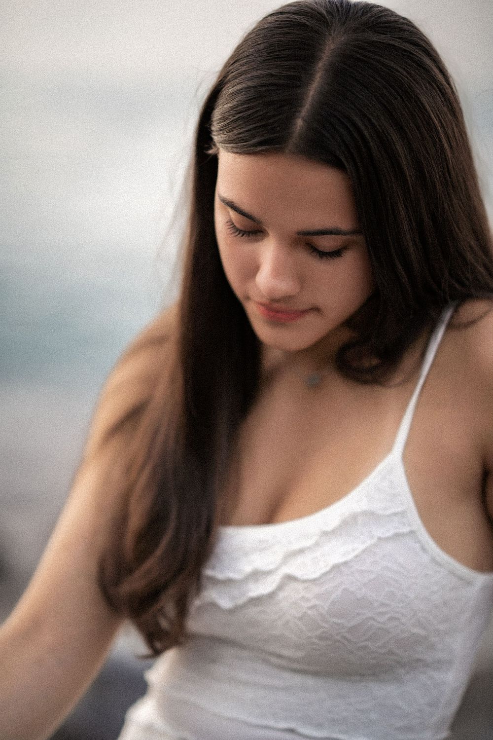 Woman in white lace camisole looking down with soft lighting in a side profile series of photos.